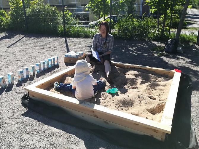 Tutkimusavustaja Sanna Lehtinen leikittämässä hiekkalaatikolla