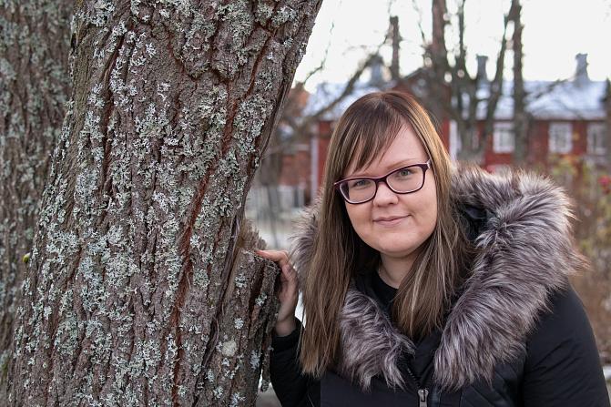 Charlotta Harju nojaa puuhun.