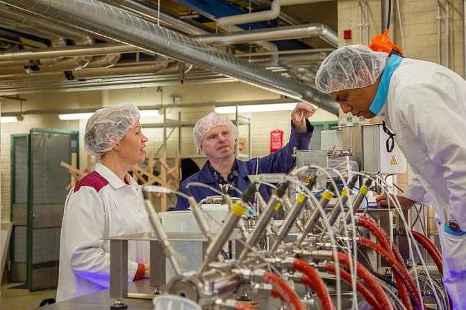 Three people at the multi-screw extruder.