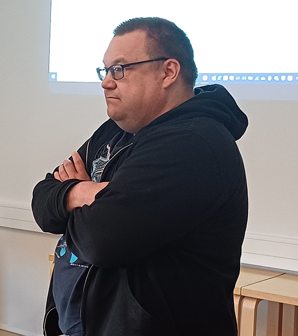 Huppariin pukeutunut mies seisomassa valkokankaan edessä