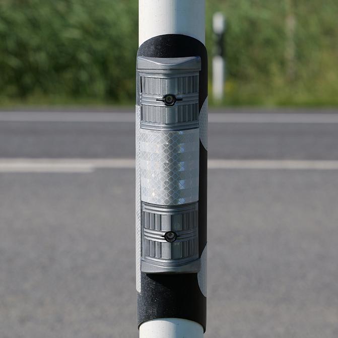 Tien vieressä oleva pylväs, johon on asennettu auton valot heijastava heijastin.