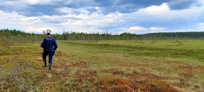 A police officer in uniform is walking in the marsh.