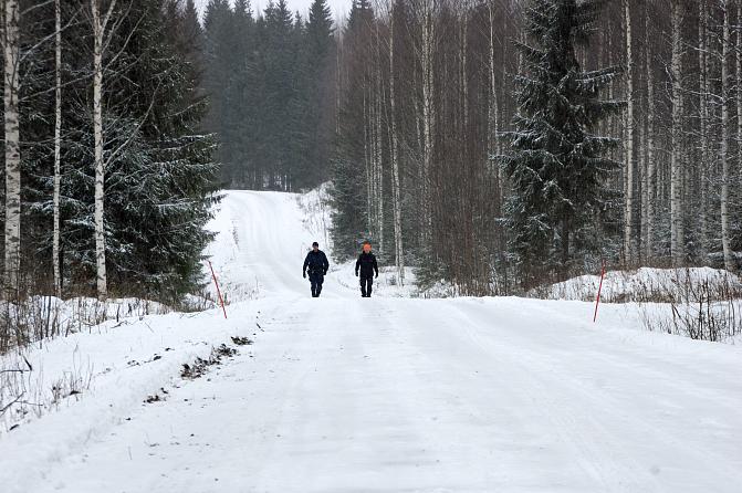 Poliisi ja erätarkastaja kävelevät metsäautotiellä.