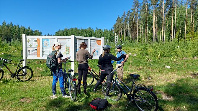 pyöräilijöitä Punkaharjun tutkimuspuiston infotauluilla