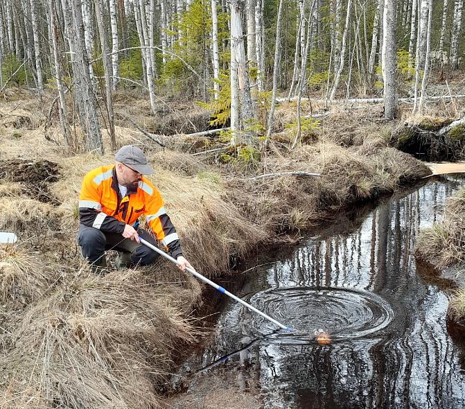 Kuvassa Luken tutkimusmestari ottamassa vesinäytettä
