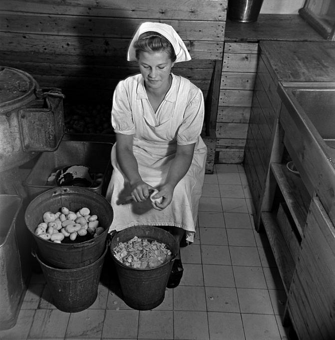 Nainen kuorii perunoita.