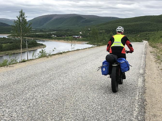  Pyöräilijä pyöräilee maantien reunassa tunturimaisemassa.