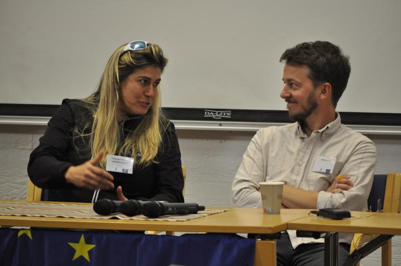  A woman and a man are discussing in a panel.