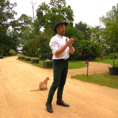 Mies seisoo pihalla ja esittelee piha-aluetta