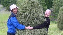 People hugging a hay bale.